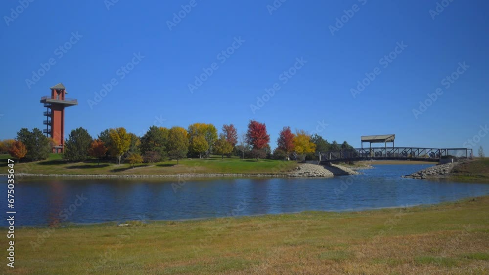 Walking across a bridge over a pond at a city park with a watchtower. Walking across a bridge over a pond at a city park with a watchtower.