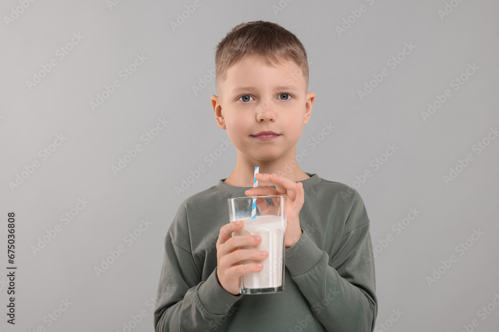 Cute boy with glass of fresh milk on light grey background Cute boy with glass of fresh milk on light grey background