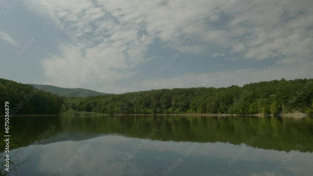Calm lake with cloud reflections in scenic landscape pan down shot Calm lake with cloud reflections in scenic landscape pan down shot