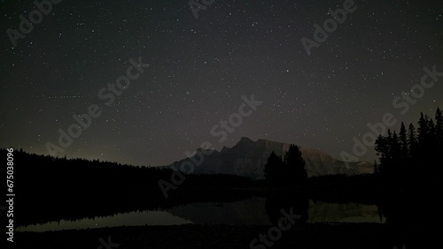 AI generated illustration of a lake amid forests and mountains at a beautiful starry night © Wirestock