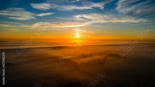 Aerial view of breathtaking landscape of the sun setting behind a rolling blanket of fog