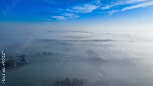 Aerial view of a small town shrouded in a misty fog, with white fluffy clouds surrounding it