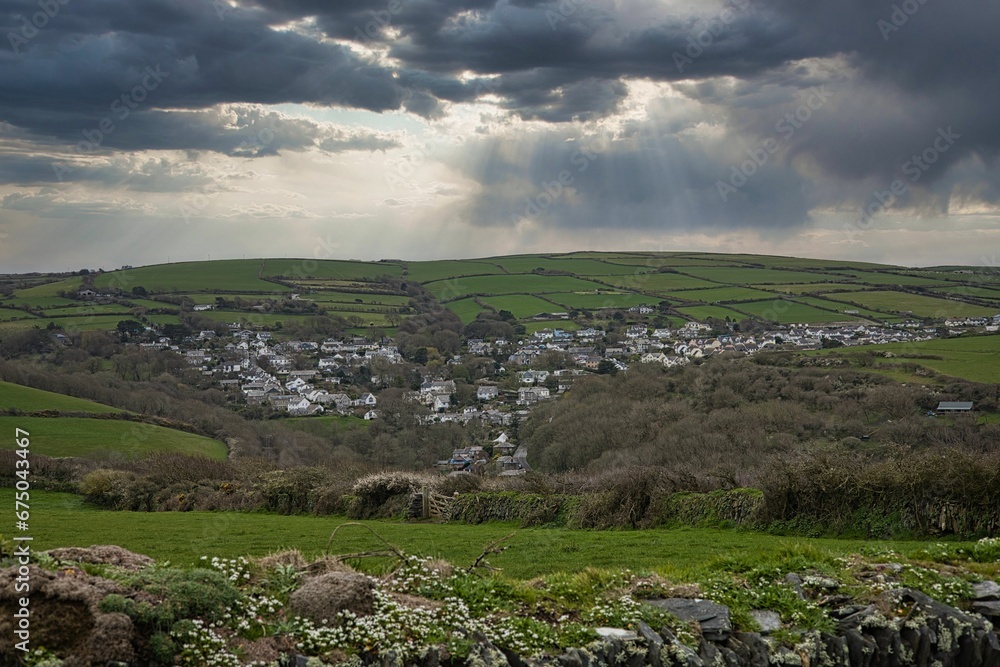 Scenic view of a lush green valley and the town of Tintagel, Cornwall under a dramatic sky