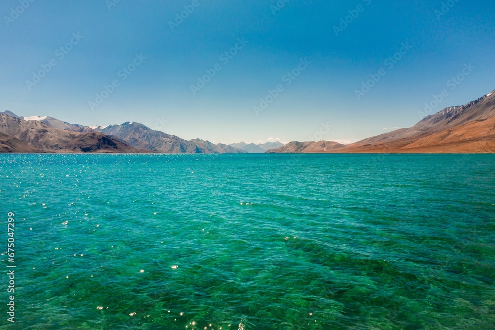 Scenic landscape image of an ocean shoreline with majestic mountains in the background