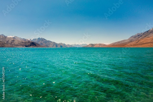 Scenic landscape image of an ocean shoreline with majestic mountains in the background