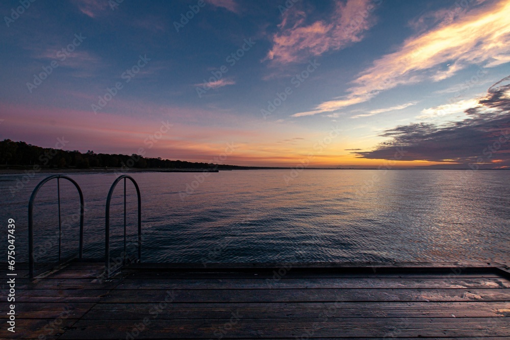 an empty dock on a body of water under a sunset