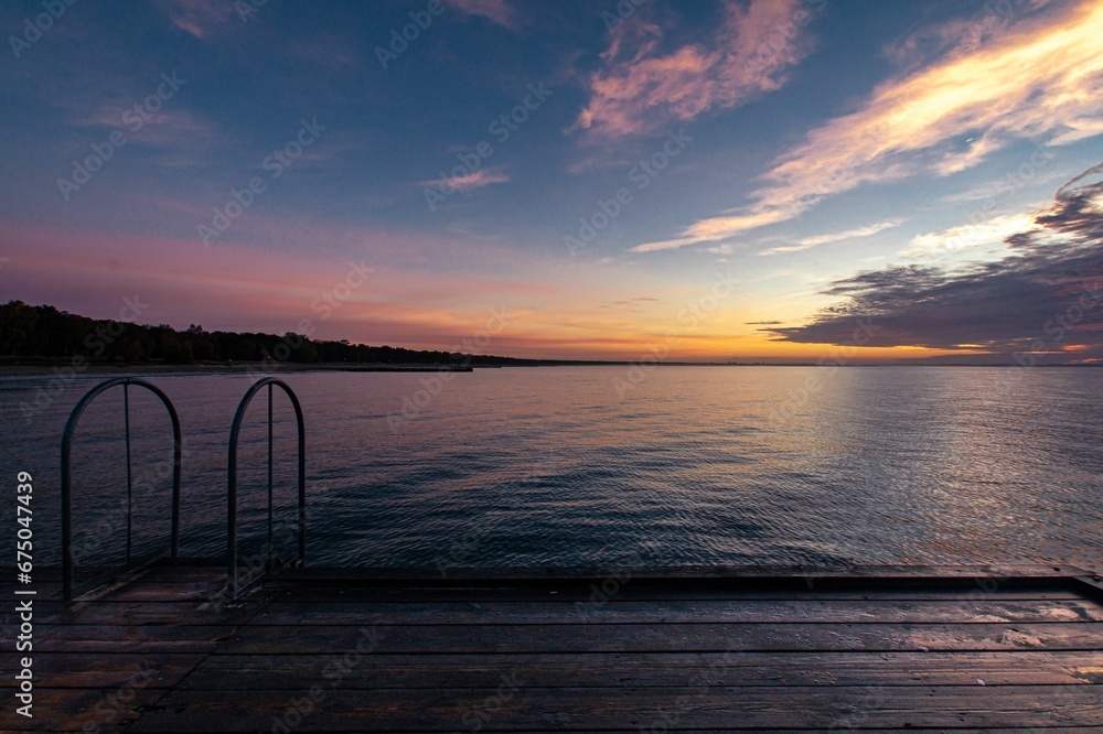 Fototapeta premium an empty dock on a body of water under a sunset