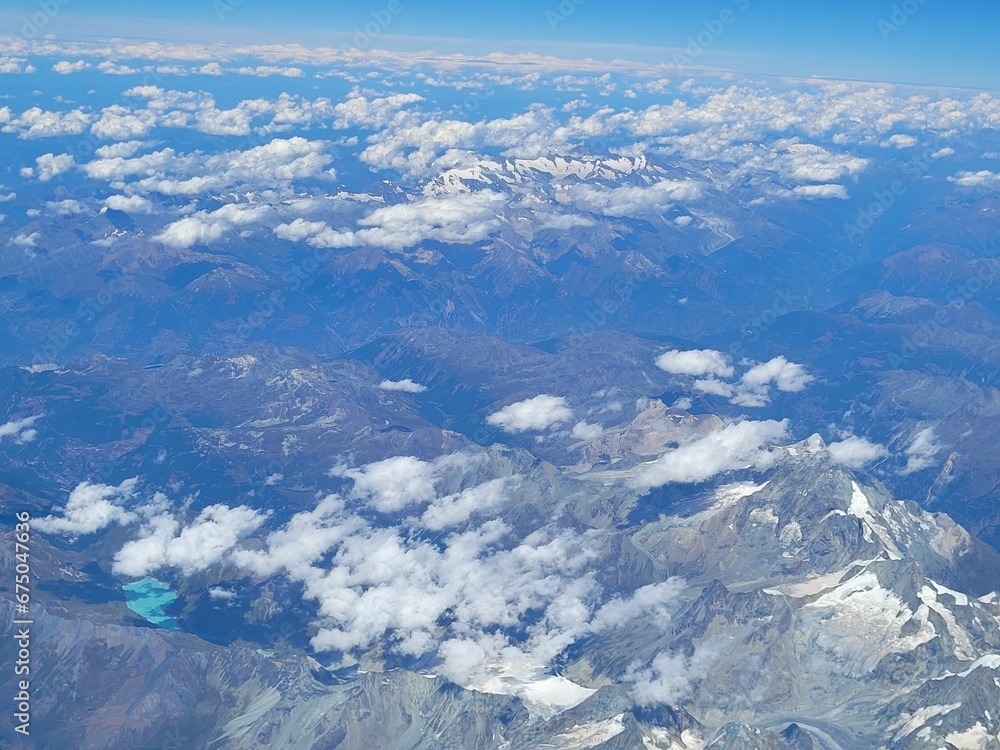 the wing of an airplane over mountains and lakes is shown