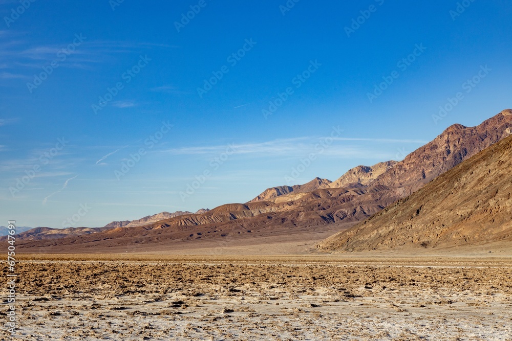 Scenic landscape shot of a mountain range in the distance, with a bright blue sky overhead