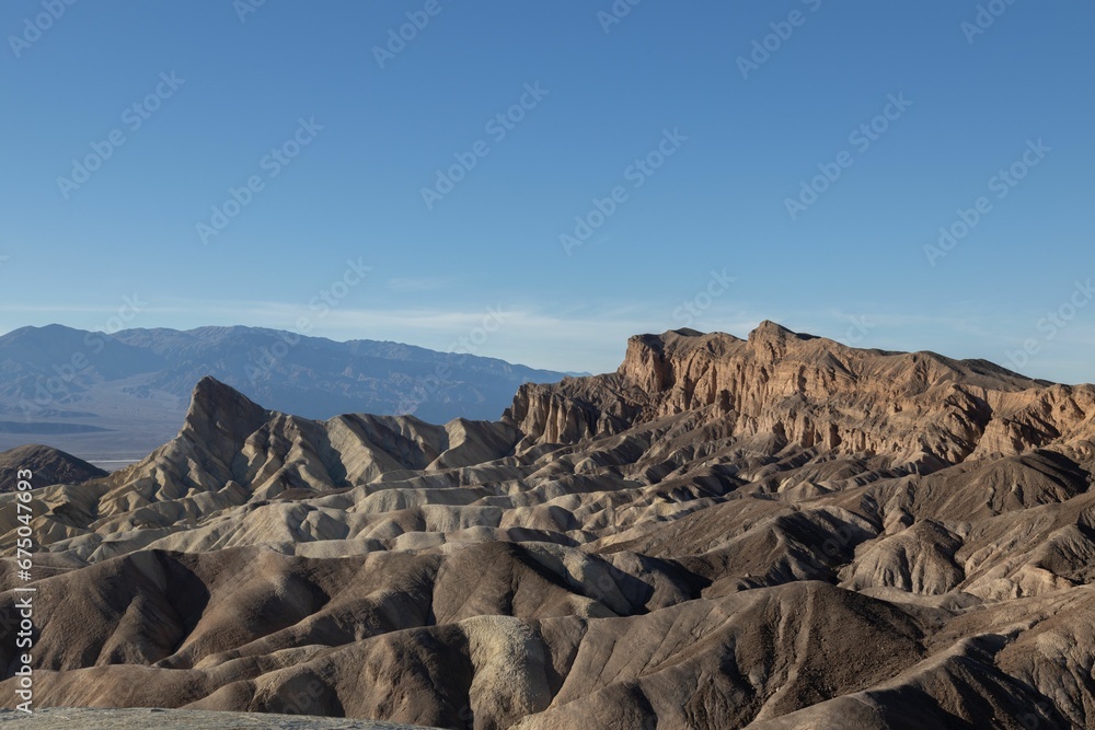 Scenic landscape shot of a mountain range in the distance, with a bright blue sky overhead