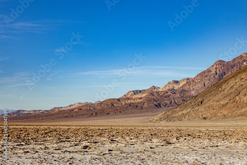 Scenic landscape shot of a mountain range in the distance, with a bright blue sky overhead