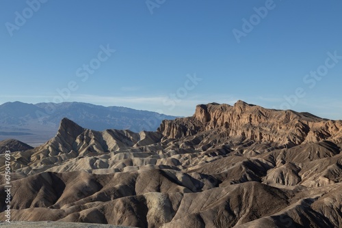 Scenic landscape shot of a mountain range in the distance  with a bright blue sky overhead