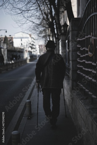 Wallpaper Mural Back shot of an old man with hat and using crutch walking on the street pavement, vertical shot Torontodigital.ca