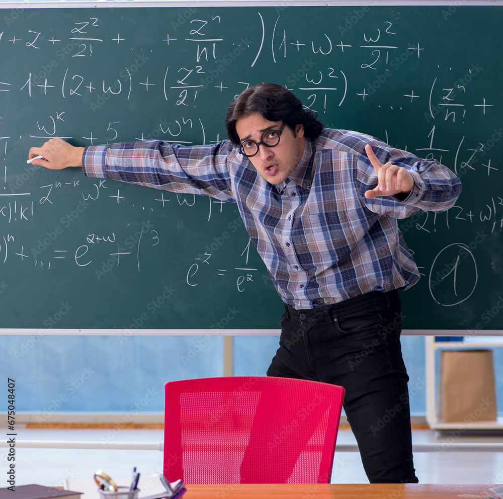 Young funny math teacher in front of chalkboard Young funny math teacher in front of chalkboard