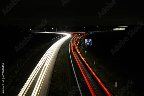 Aerial long-exposure view of car light trails on a highway road at night