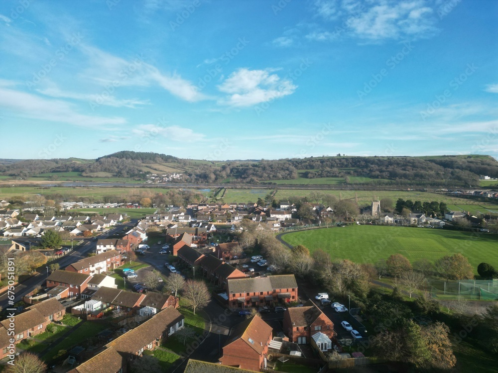 Fototapeta premium Aerial view of rural houses in a green field near the sea in Seaton, Devon