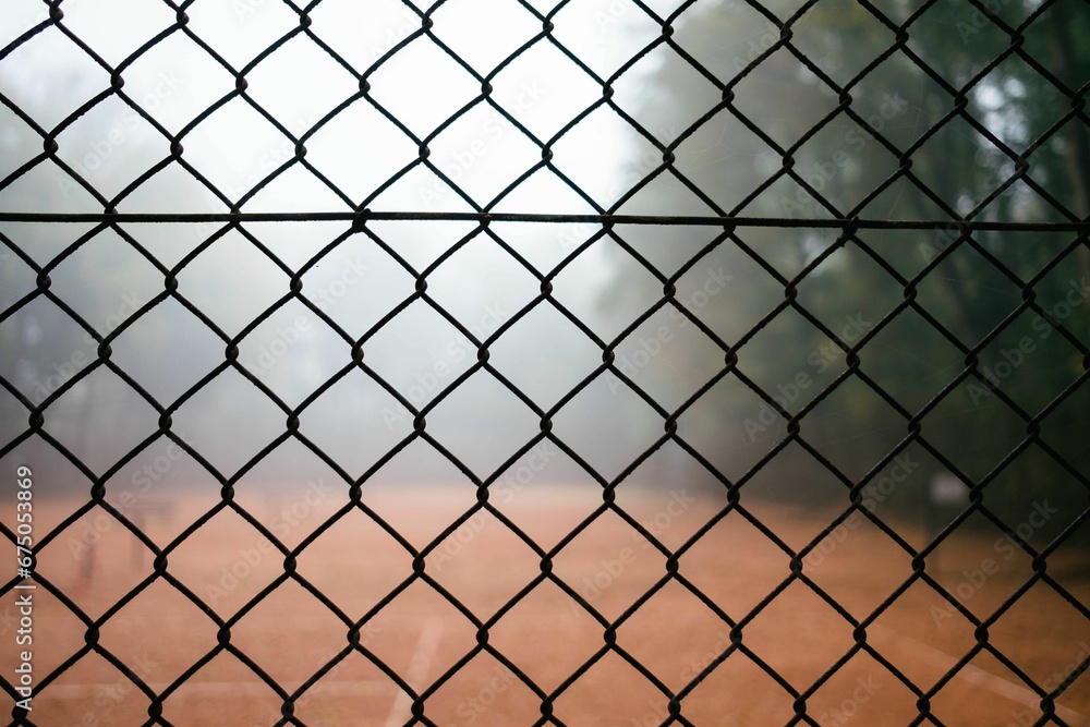 Horizontal shot on an empty tennis court in the forest in fog through a fence. Horizontal shot on an empty tennis court in the forest in fog through a fence.