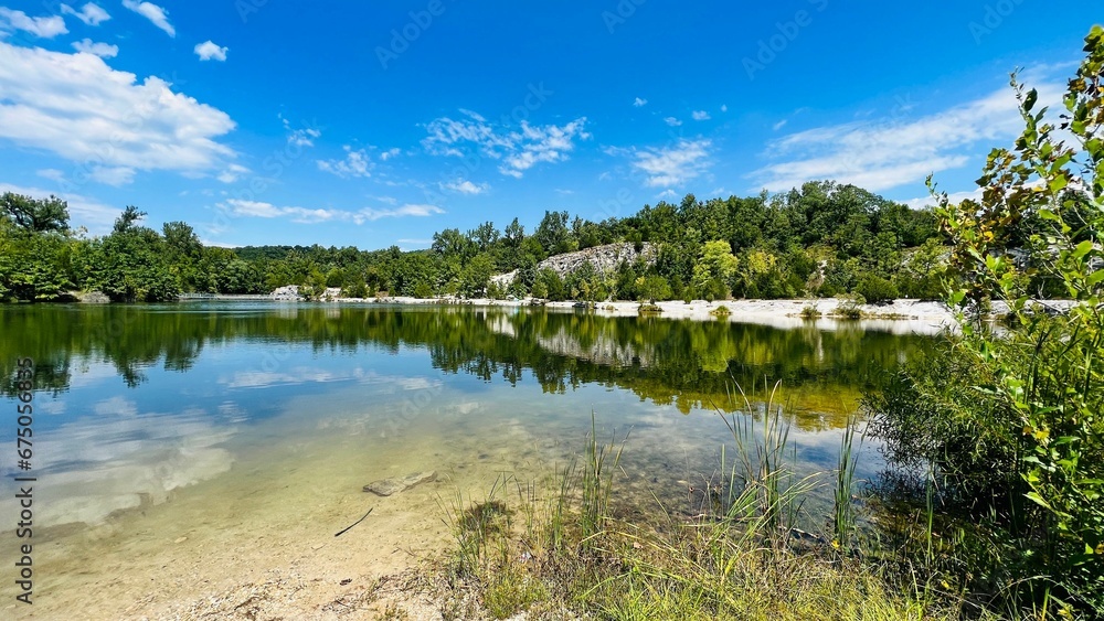 Stunning view features a crystal-clear lake surrounded by lush green trees.