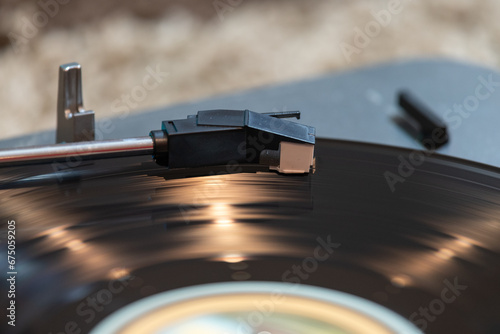 Close up of a vinyl record spinning on a turntable with light reflections accenting the surface of the disc.