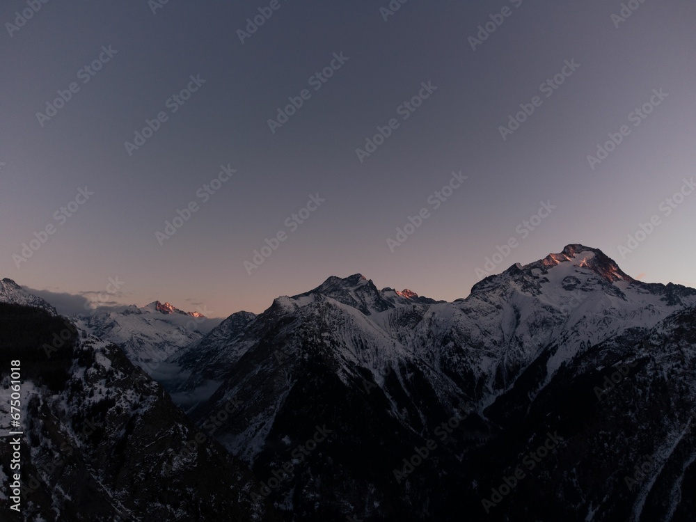 Snowy mountain tops at sunrise with clear skies behind them