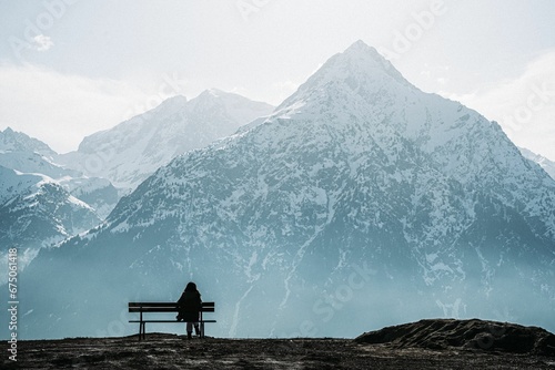 Canvas-taulu Oman sitting on a wooden bench with snow capped mountains in the background