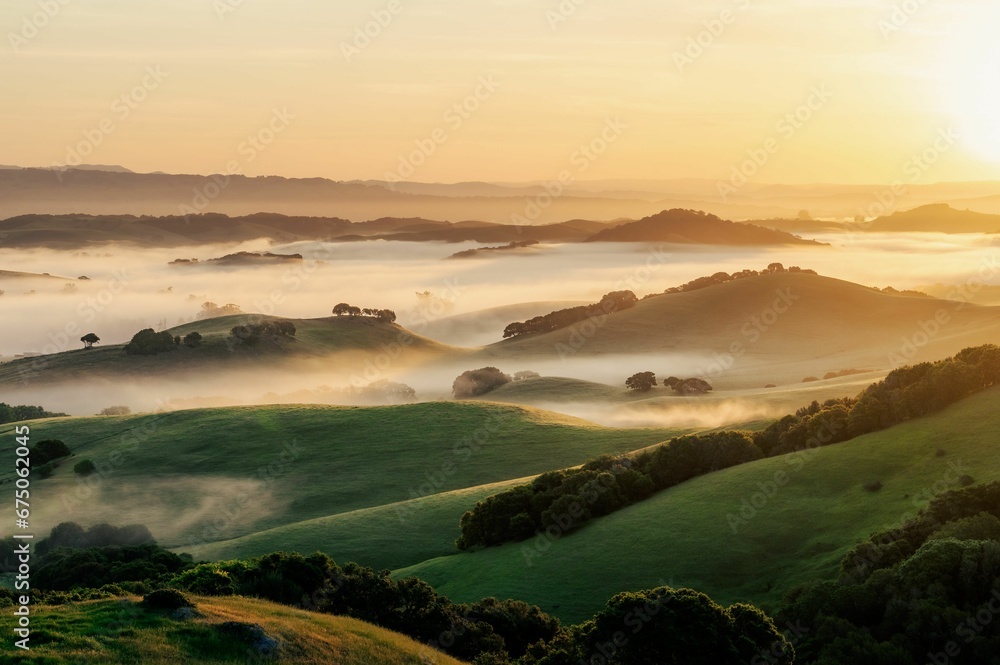 Scenic landscape of a rolling green hills with clouds at sunset
