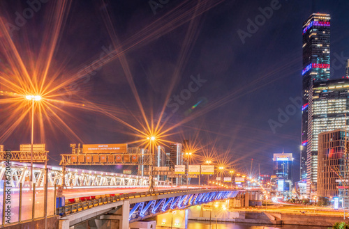 The scyscrapers of the Moscow City at night and the Dorogomilovsky bridge with illumination. Translation of text - street names: Krasnopresnenskaya, center, etc.