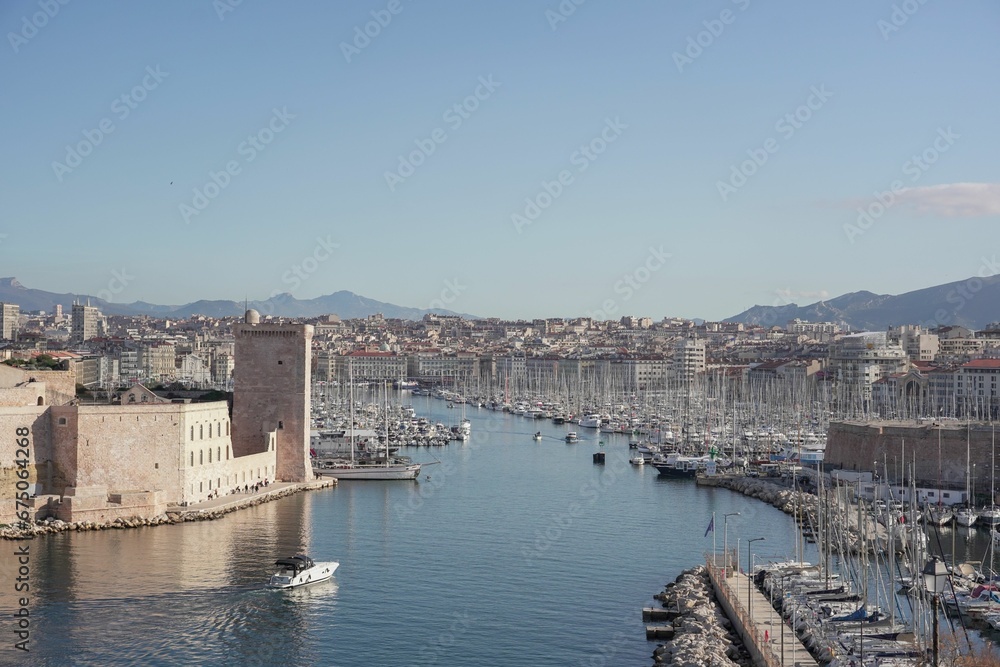 Fleet of sailing vessels docked side-by-side at a harbor in an urban setting in Marseille, France