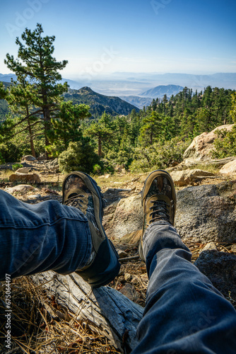 A man wearing hiking boots looking at the scenic views of Santa Rosa mountains near Toro Peak in Southern California.