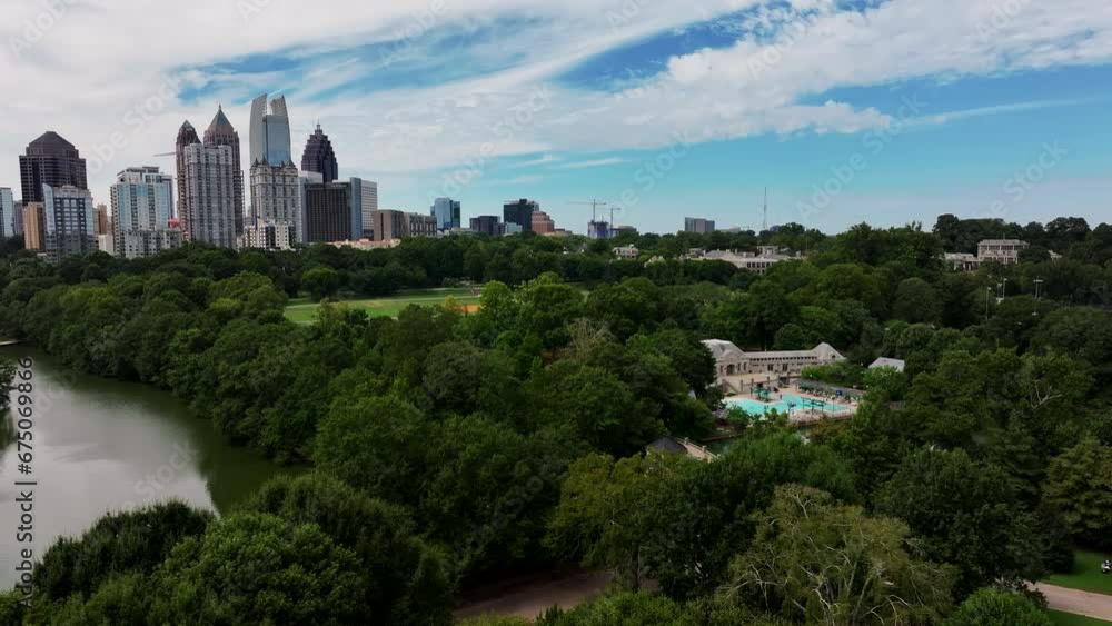 Aerial view of green trees in large park. Sliding reveal of midtown high rise office or residential buildings in metropolis. Atlanta, Georgia, USA Aerial view of green trees in large park. Sliding reveal of midtown high rise office or residential buildings in metropolis. Atlanta, Georgia, USA