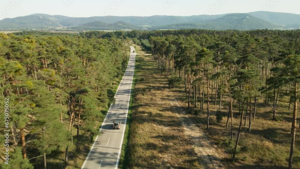 Offroad car passing by asphalt road in the pine tree forest. Landscape with mountains. Peaceful roadtrip with car in beautiful nature. Offroad car passing by asphalt road in the pine tree forest. Landscape with mountains. Peaceful roadtrip with car in beautiful nature.