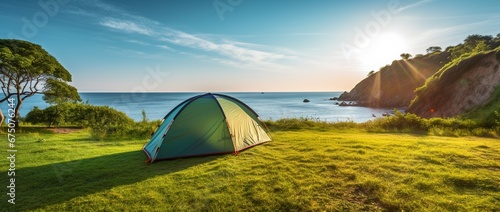 Camping tent and camping equipment on green grass with sea view background