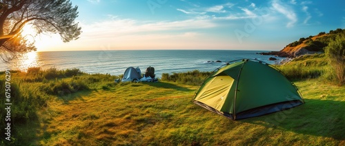 Camping tent and camping equipment on green grass with sea view background