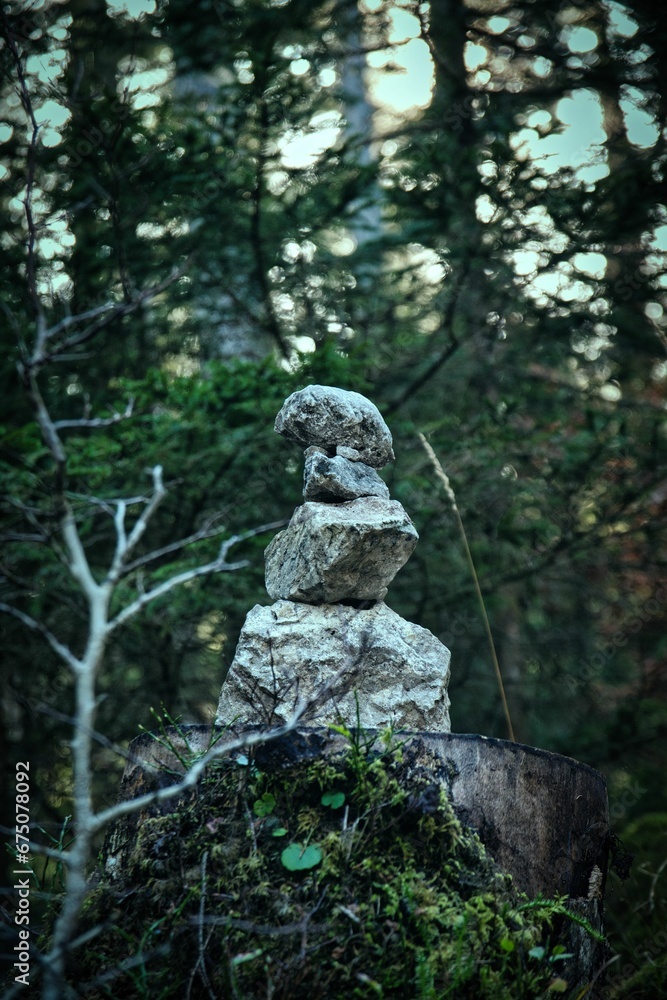 Collection of stones stacked atop one another in a lush forest setting.