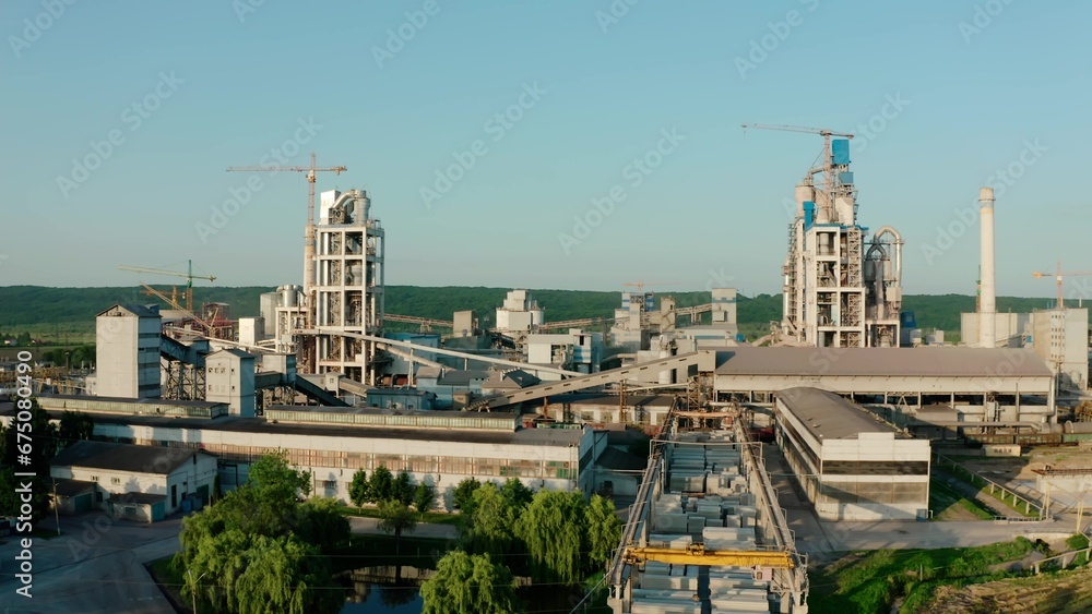 Cement plant with high factory structure at industrial production area at sunset. Aerial drone