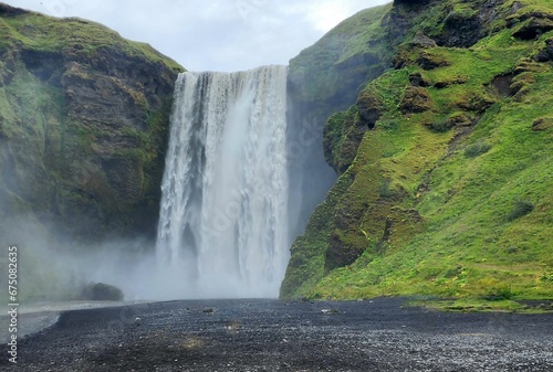 there is a waterfall flowing over a hill next to a black sand beach