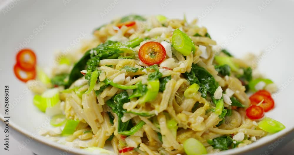 Asian noodles with coriander chilli and scallions. Plant-based child noodle bowl shot in 4k with shallow depth of field. Rotating footage of spicy vegan vegetarian healthy bowl food. Asian noodles with coriander chilli and scallions. Plant-based child noodle bowl shot in 4k with shallow depth of field. Rotating footage of spicy vegan vegetarian healthy bowl food.