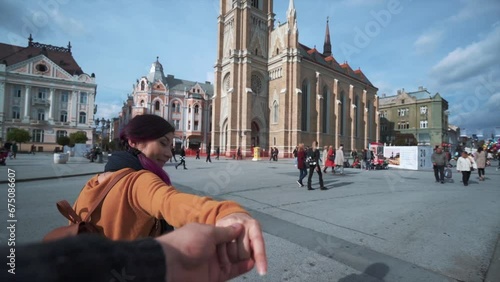 Follow me romantic concept. Young asian woman with purple hair holding her boyfriend's hand. Smiling model running turn around and smile. Novi sad town cityscape, Serbia. Tourist girl travelling photo