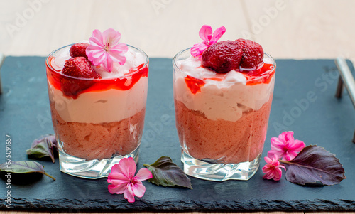 Two glasses of Raspberry Mousse Parfait decorated with flowers over a black surface photo