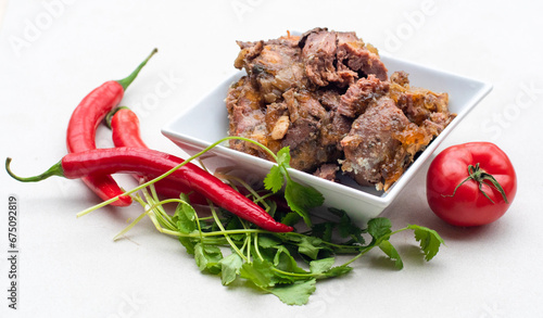 A bowl of meat decorated with tomatoes parsley and red chili peppers photo