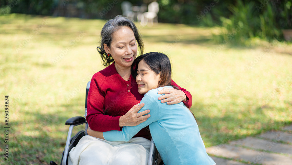 Asian senior woman in wheelchair with happy daughter. Family relationship retired woman sitting on wheelchair in the park age care at retirement home. Asian senior woman in wheelchair with happy daughter. Family relationship retired woman sitting on wheelchair in the park age care at retirement home.