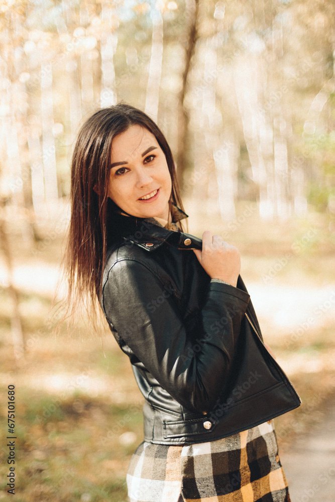 A beautiful girl in jeans and a plaid shirt walks in a birch grove. Portraits of a brunette girl in nature, in the autumn forest A beautiful girl in jeans and a plaid shirt walks in a birch grove. Portraits of a brunette girl in nature, in the autumn forest