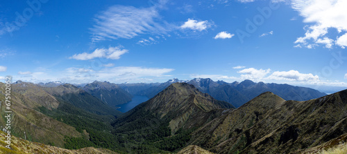 Summit of the Kepler track with a view of a lake in the middle of a mountain range during a sunny day, New Zealand