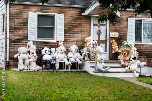 Teddy bears of different colors, shapes and sizes in front of an American house. © halitomercamci