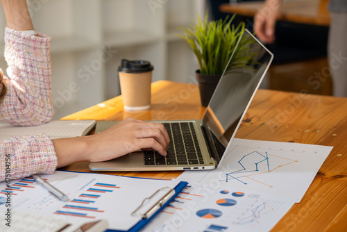 Young Asian businessman working with laptop, checking graphs, company budget reports, production control. Operational inspection cost plus price Close-up pictures