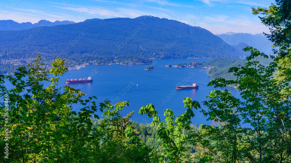 Fototapeta premium Oil tankers on pristine waters of Burrard Inlet, backed by forested mountains.