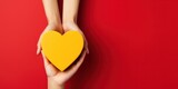 Hands holding heart and gift box on a yellow and red  background, giving love and generosity to loved ones.