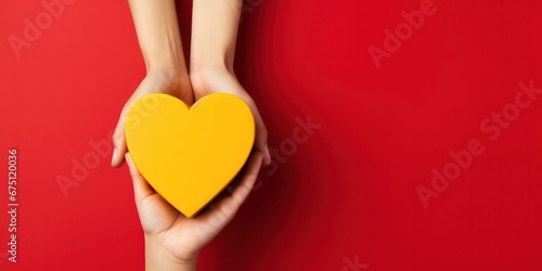 Hands holding heart and gift box on a yellow and red background, giving love and generosity to loved ones.