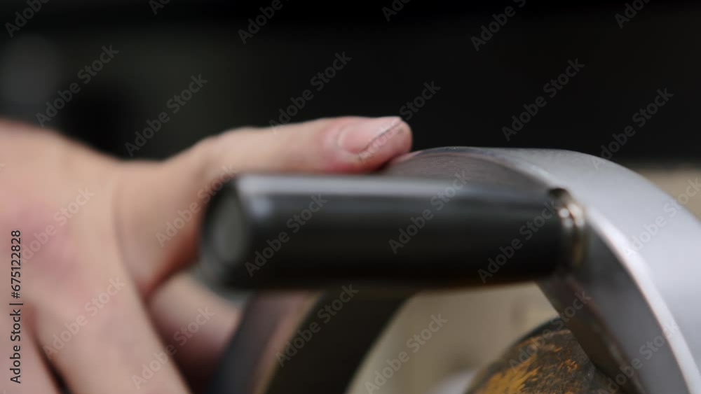 A factory worker operating the wheel of an automatic grinding machine A factory worker operating the wheel of an automatic grinding machine