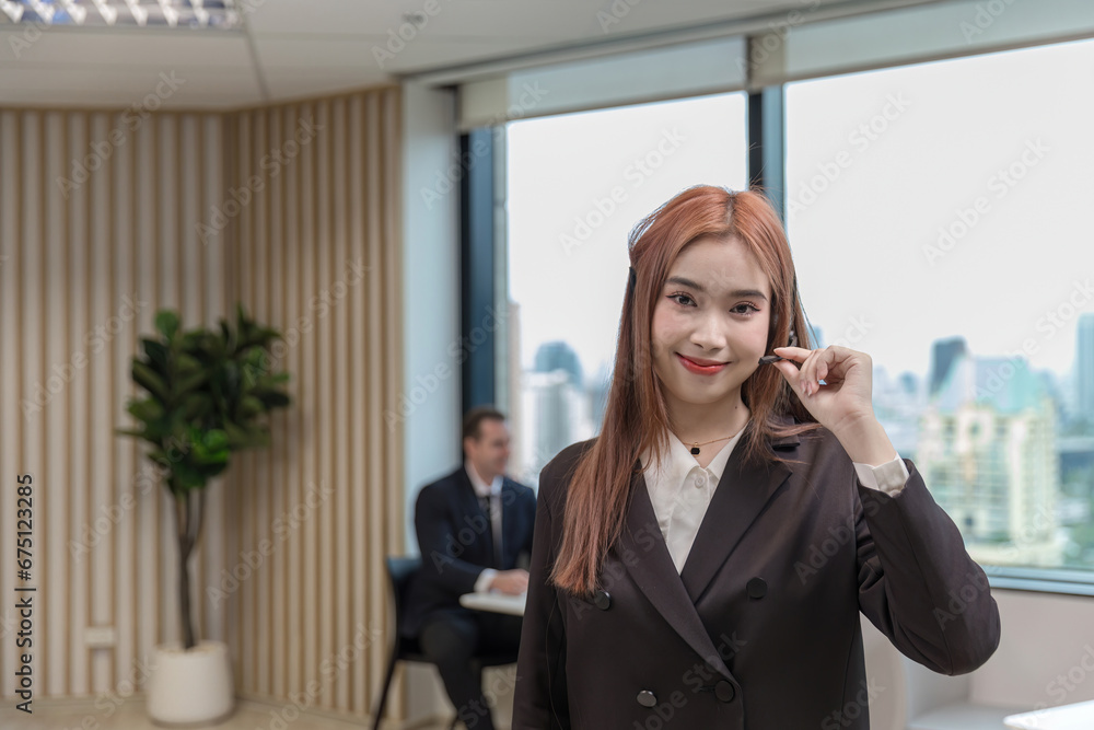 Fototapeta premium Call center business woman talking on headset. Call center worker accompanied by her team. Customer service executive working at office. 